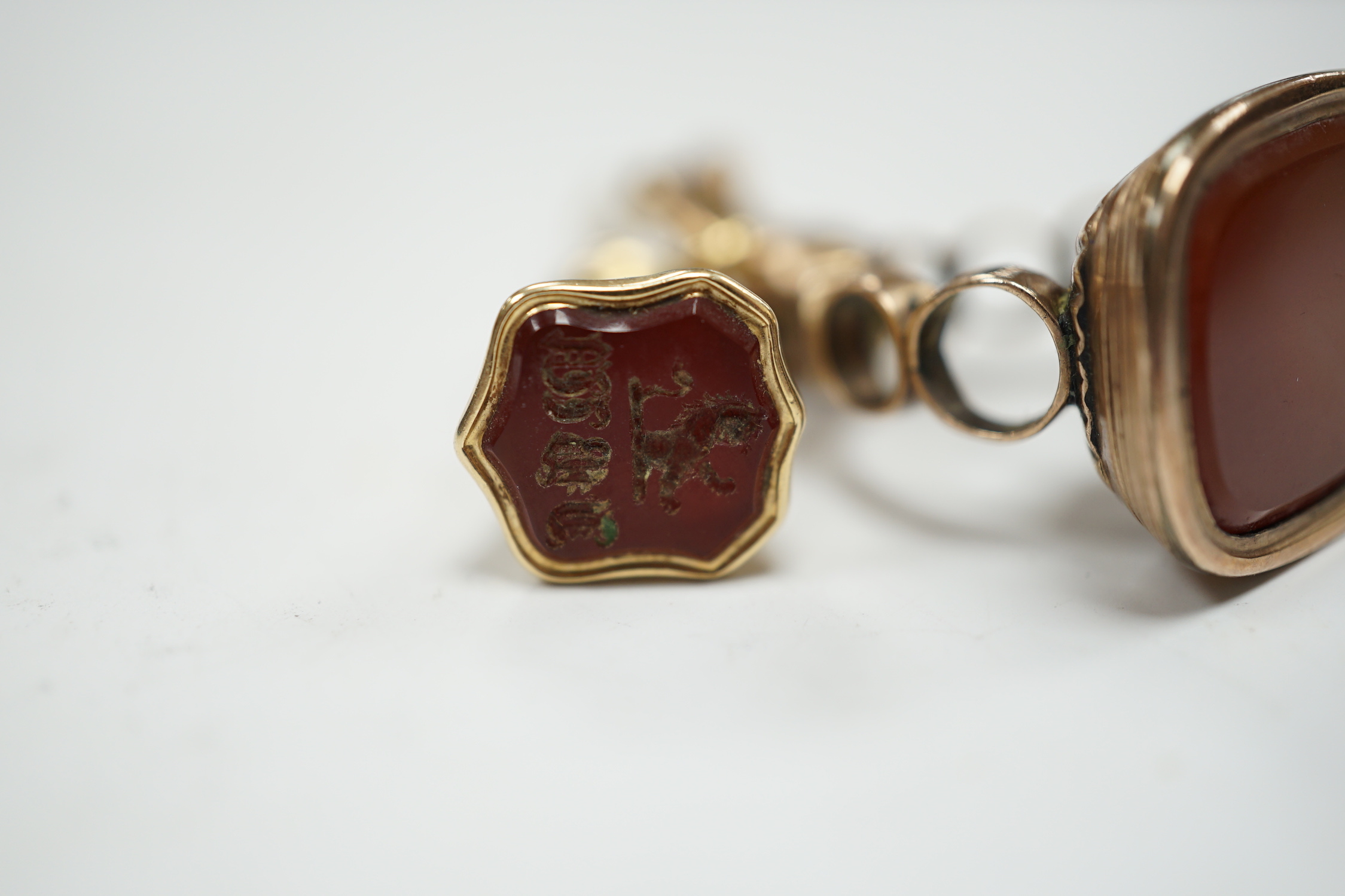 A 19th century engraved yellow metal overlaid and carnelian set trumpet shaped watch key, the matrix carved with crest and initial, 51mm, together with a 19th century gold plated and carnelian set fob.